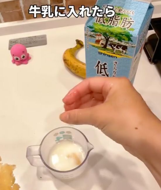 牛乳を入れたグラスに冷凍したバナナを割り入れた様子