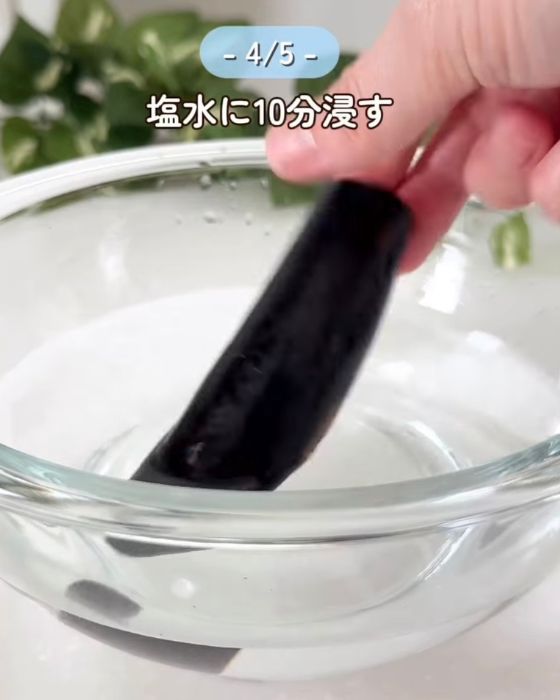 ヘタを落として半分に切ったナスを塩水に漬ける様子