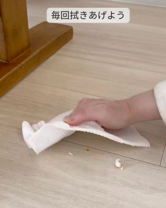 床に落ちた食べかすを雑巾で拭き取る様子