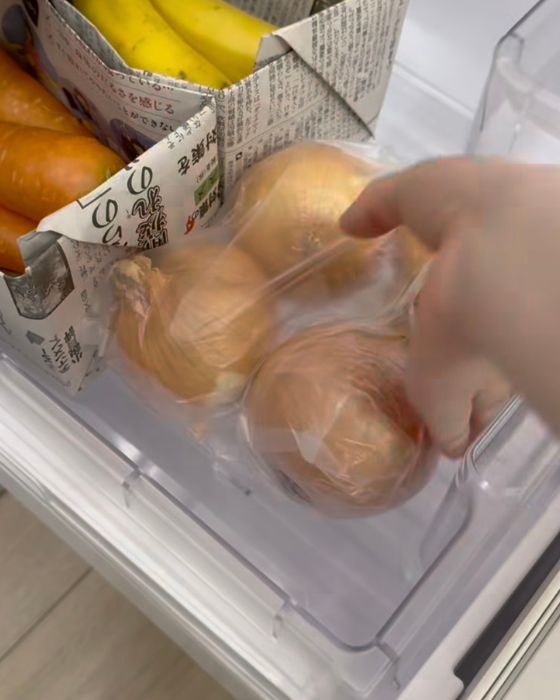 ポリ袋に入れた玉ねぎを冷蔵庫の野菜室に入れる様子