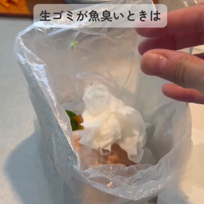 魚を拭いたキッチンペーパーを生ゴミを入れたビニール袋に捨てる様子