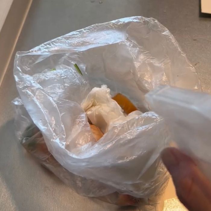 魚を拭いたキッチンペーパーを入れた生ゴミのビニール袋に『クエン酸スプレー』を吹きかける様子