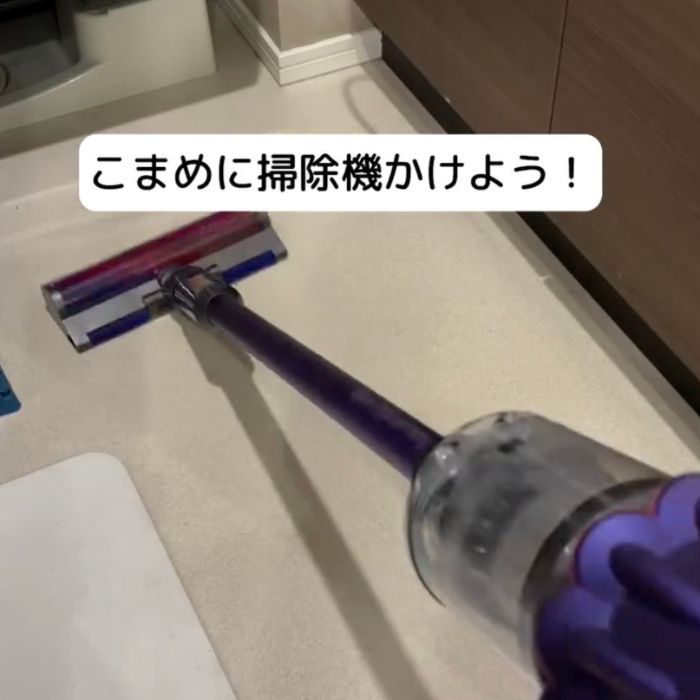 洗面所の床に掃除機をかける様子