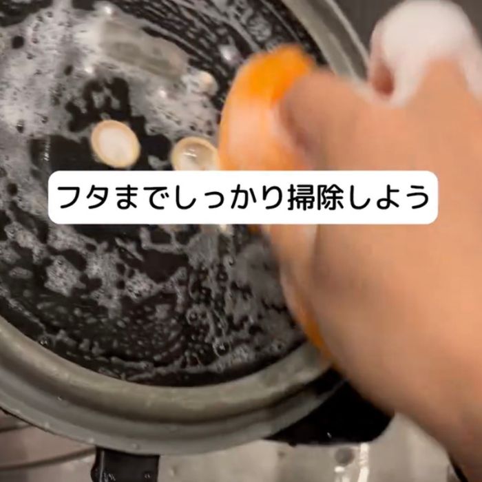 炊飯器の内蓋を洗剤を付けたスポンジで洗う様子