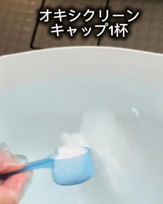 お湯を入れたバケツにキャップ1杯の『オキシクリーン』を入れる様子