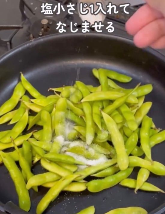 フライパンに入れた枝豆に塩をかける様子