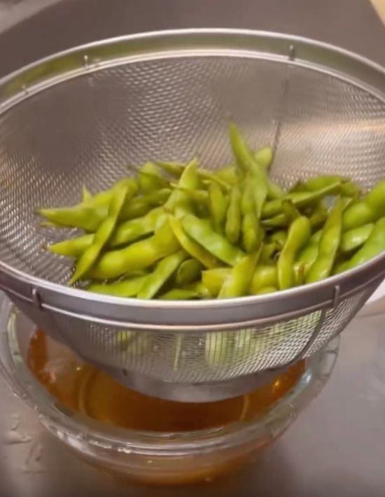 ゆでた枝豆をザルにあげて水気を切る様子