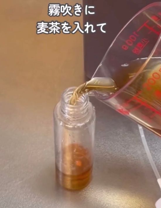 スプレーボトルに麦茶を入れる様子