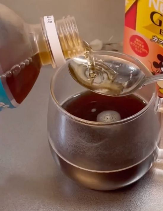 作ったインスタントコーヒーの上でティースプーンに麦茶を注ぐ様子