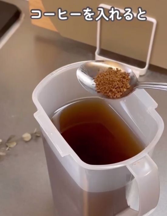 麦茶ポットの上でインスタントコーヒーを入れたティースプーンを持っている様子