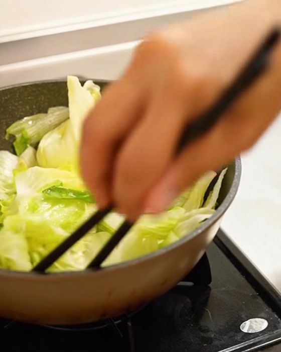 フライパンに入れたレタスを箸で返す様子