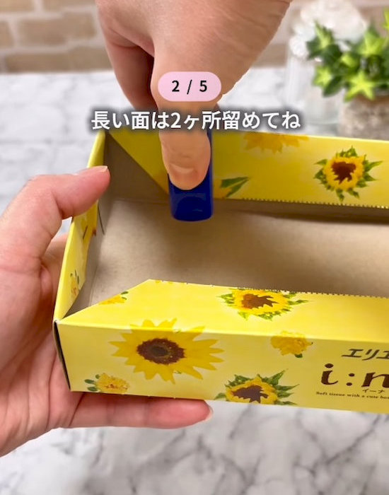 ティッシュの箱をホッチキスでとめている様子