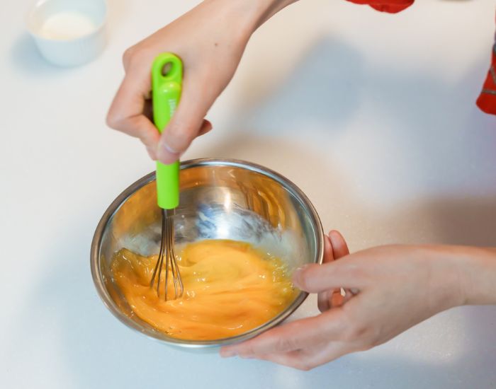 ボウルに割り入れた卵を泡立て器で混ぜる様子