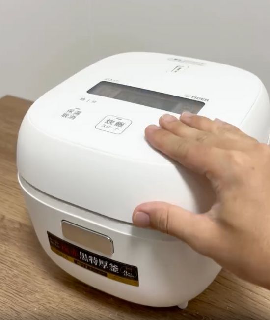 炊飯器の上に手をのせている様子
