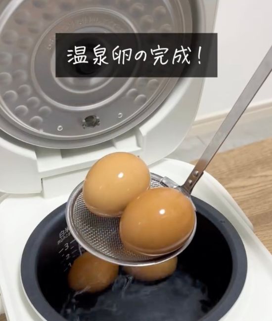炊飯釜から網じゃくしで卵を取り出す様子