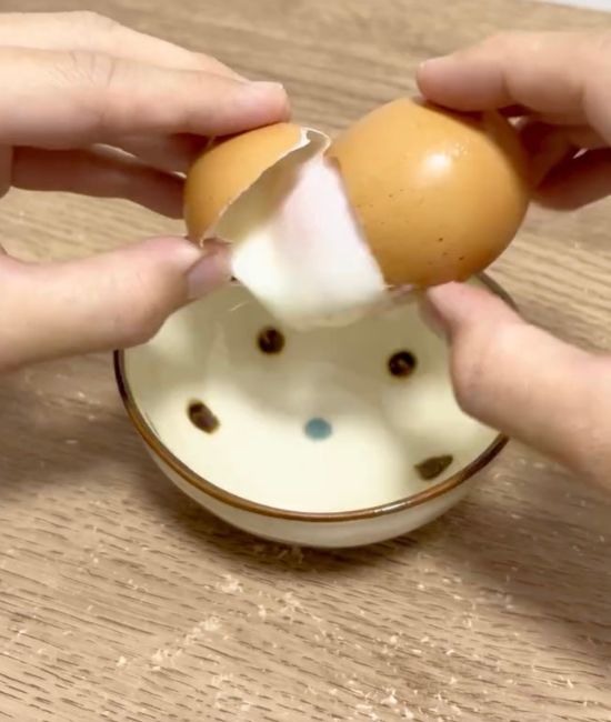 卵の殻を割って中身を小皿に出す様子