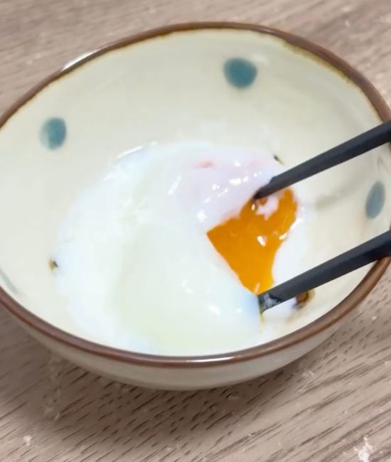 小皿に出した温泉卵を箸で割る様子