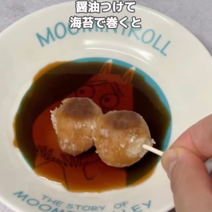 ちぎった『ポン・デ・リング』を爪楊枝にさして小皿に出した醤油をつける様子