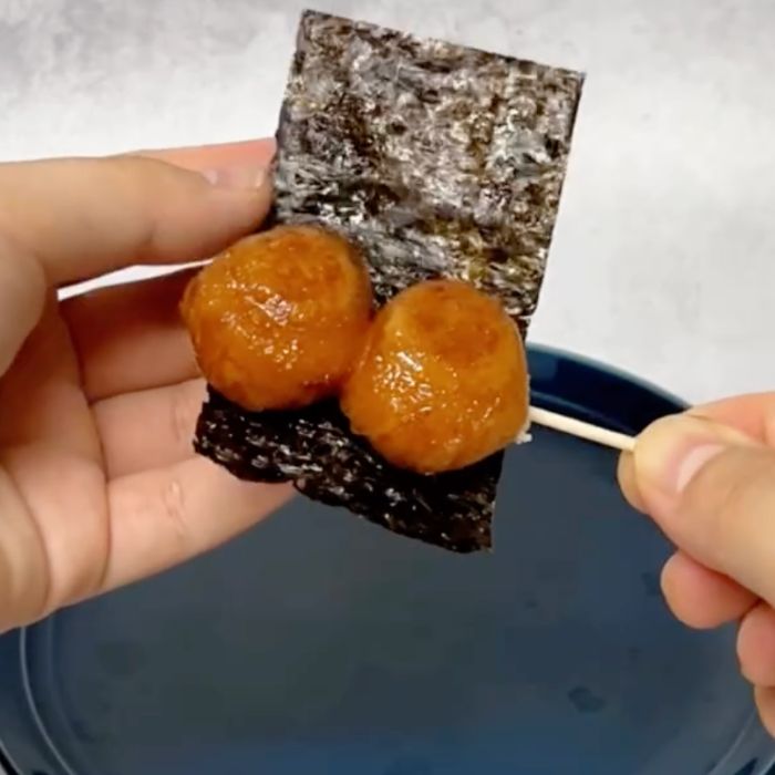 爪楊枝にさして醤油をつけた『ポン・デ・リング』に焼きのりを巻く様子