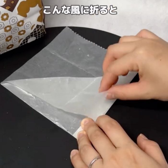 『2つ折りになった状態』の包み紙の上にある角を1枚だけ折る様子