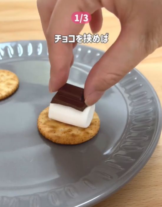 クラッカーとマシュマロの上にチョコレートをのせる様子