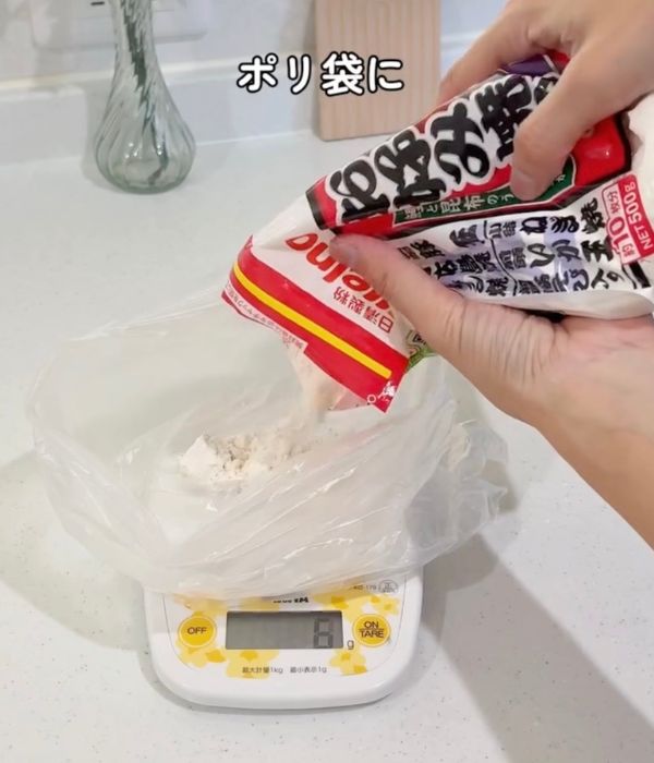 キッチンスケールに置いたビニール袋にお好み焼き粉を入れる様子