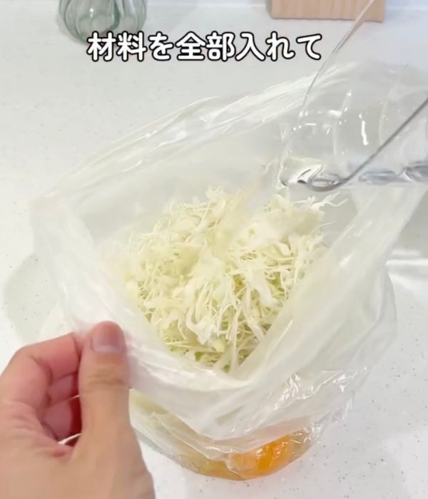 お好み焼きの材料を入れたビニール袋に水を入れる様子