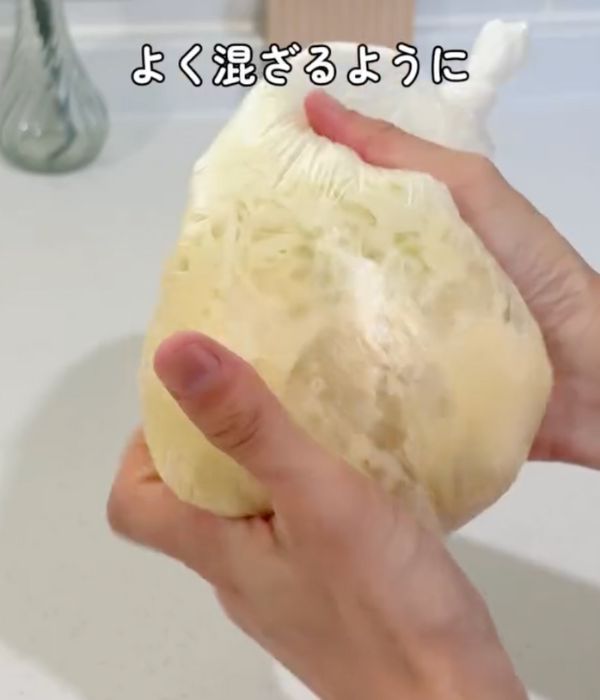 お好み焼きの材料を入れたビニール袋の口を閉じて外側からもむ様子