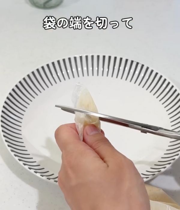 お好み焼きの材料を入れたビニール袋の底の角をハサミで切る様子