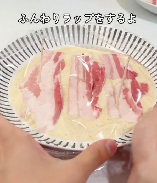 豚肉をのせたお好み焼きの生地を入れた耐熱皿にラップをかけた様子