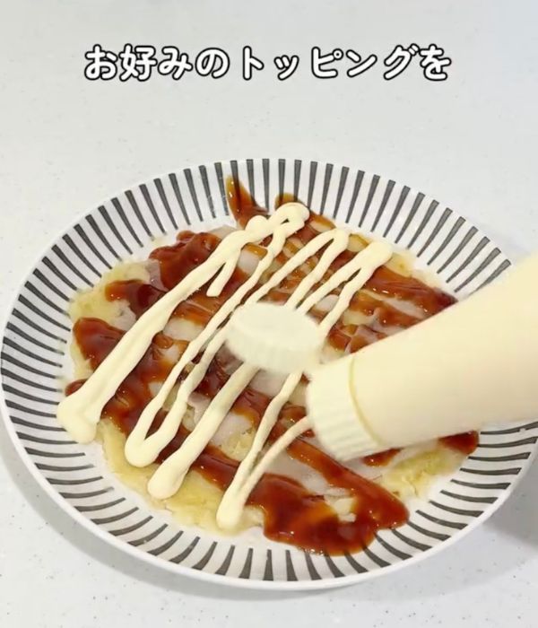 加熱したお好み焼きにマヨネーズをかける様子