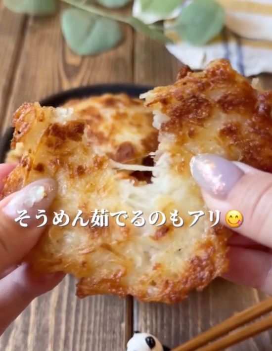 そうめんで作ったチーズおつまみを手で半分に割く様子