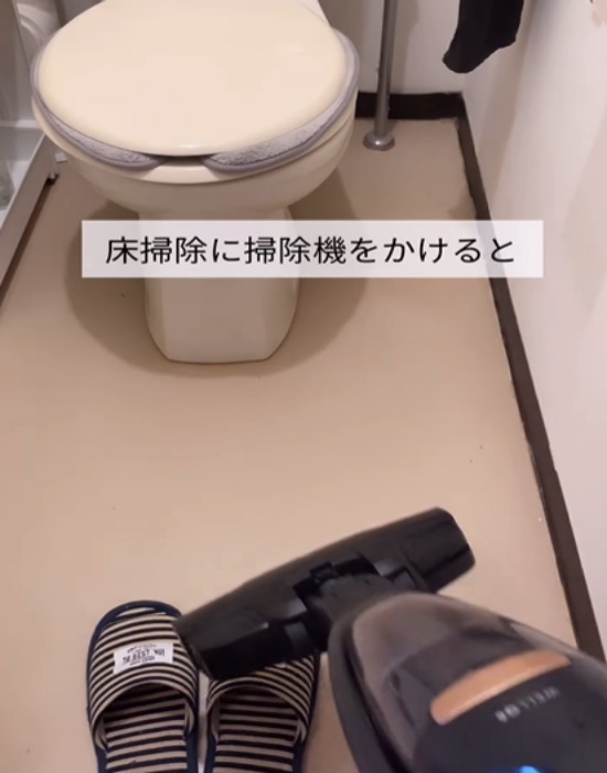 トイレの床に掃除機をかける様子