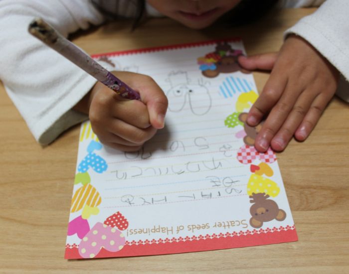 子供が鉛筆で手紙を書いている様子
