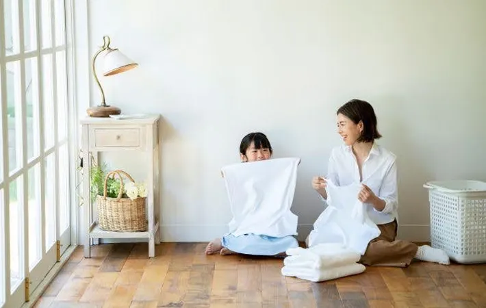 タオルをたたむ女性と子供の写真