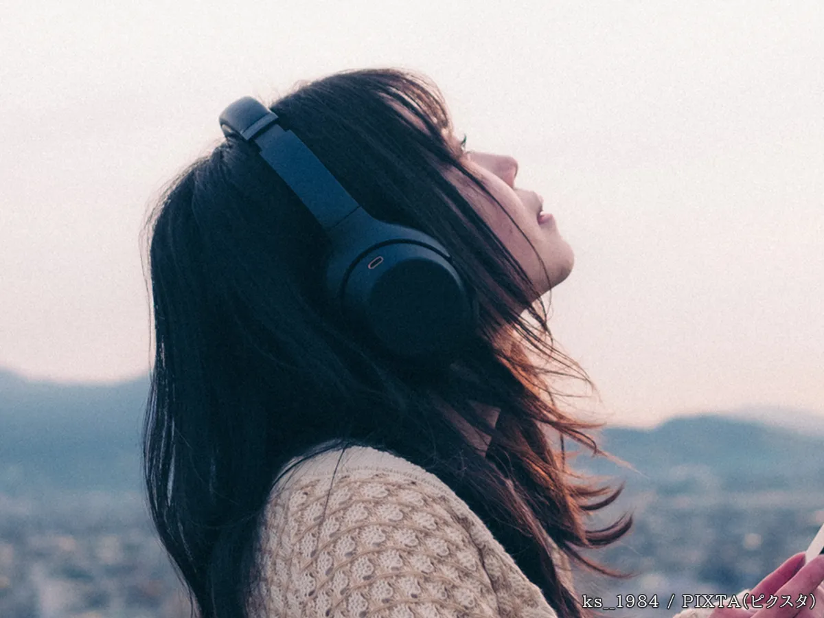 音楽を聴きながら空を見上げる女性の写真