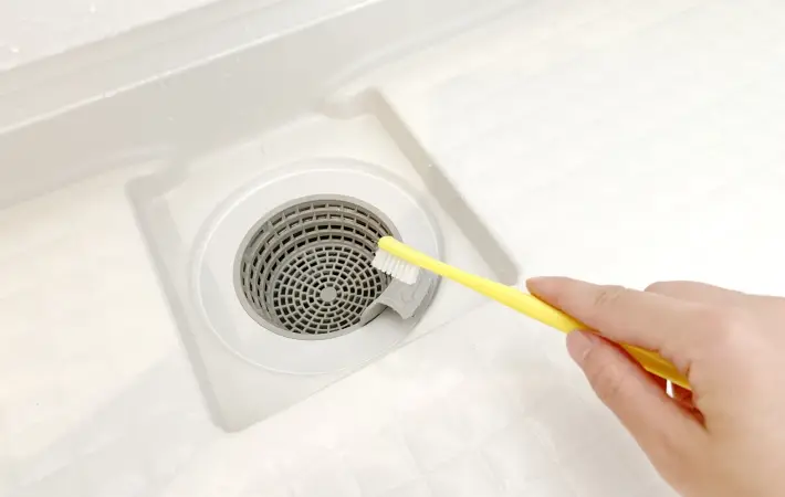 排水口を歯ブラシで掃除している様子