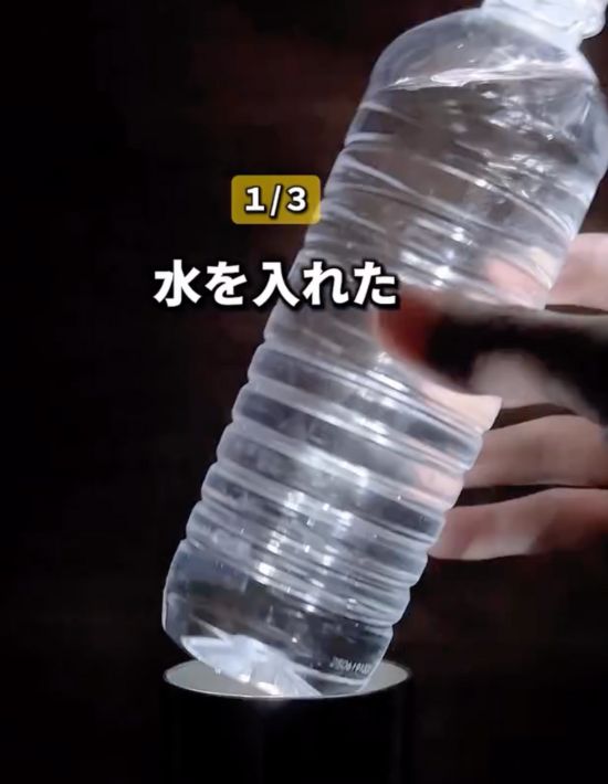 水を入れたペットボトルをコップの中に入れようとしている様子