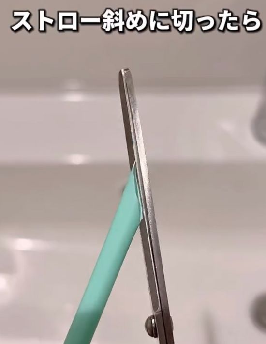 プラスチック製のストローをはさみで斜めに切る様子