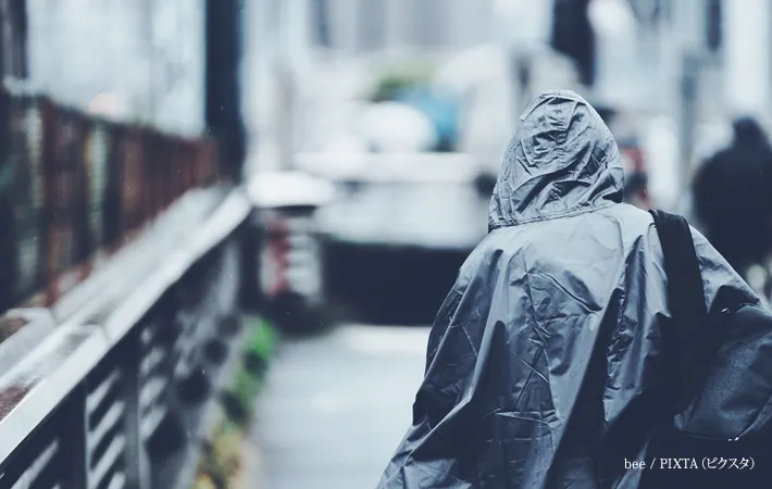 『レインコートを着た歩行者の後ろ姿』の写真