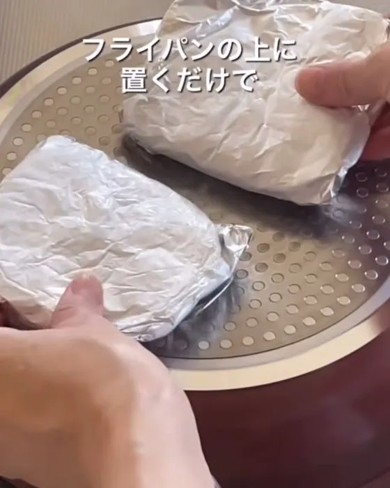 肉の入ったアルミホイルをフライパンの上にのせている様子