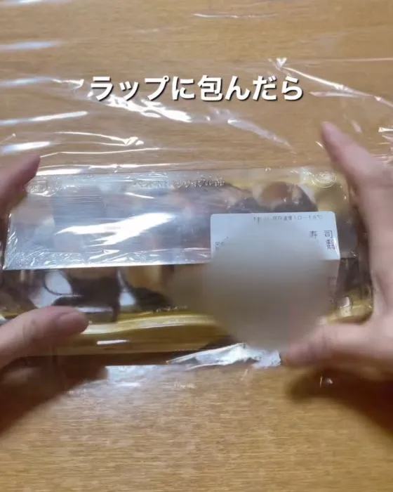 寿司のパックをラップで包んでいる様子