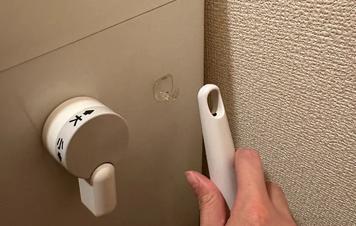 吸着させた『何度でも貼ってはがせるフィルムフック 固定タイプ 小』に『スクラビングバブル 流せるトイレブラシ』を吊るす画像（撮影：grape編集部）