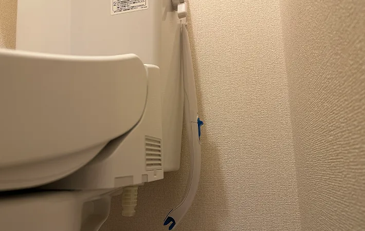 吸着させた『何度でも貼ってはがせるフィルムフック 固定タイプ 小』に『スクラビングバブル 流せるトイレブラシ』を吊るす画像（撮影：grape編集部）