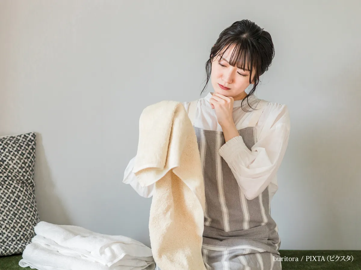 『洗濯物の仕上がりに悩む主婦の女性』の写真