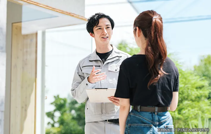 作業服を着た男性と話を聞く女性の写真