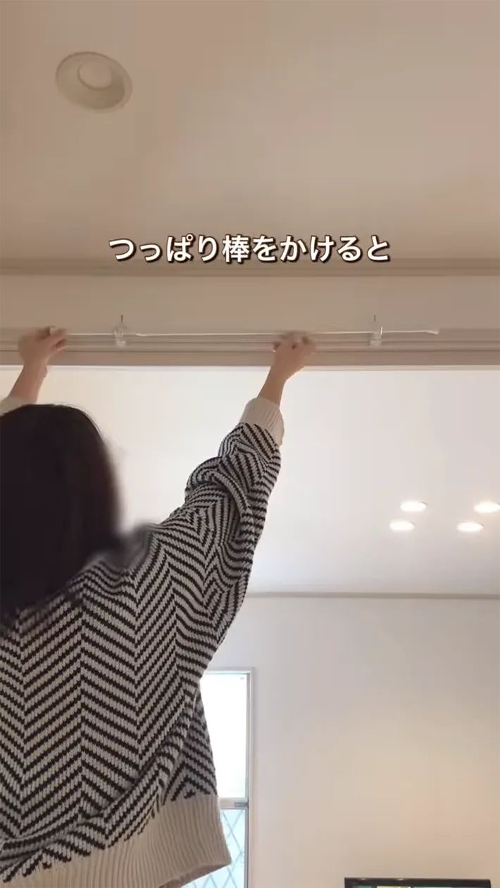 ドアの上に突っ張り棒をかける女性の写真