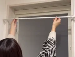 突っ張り棒を風呂の出入り口にかける女性の写真