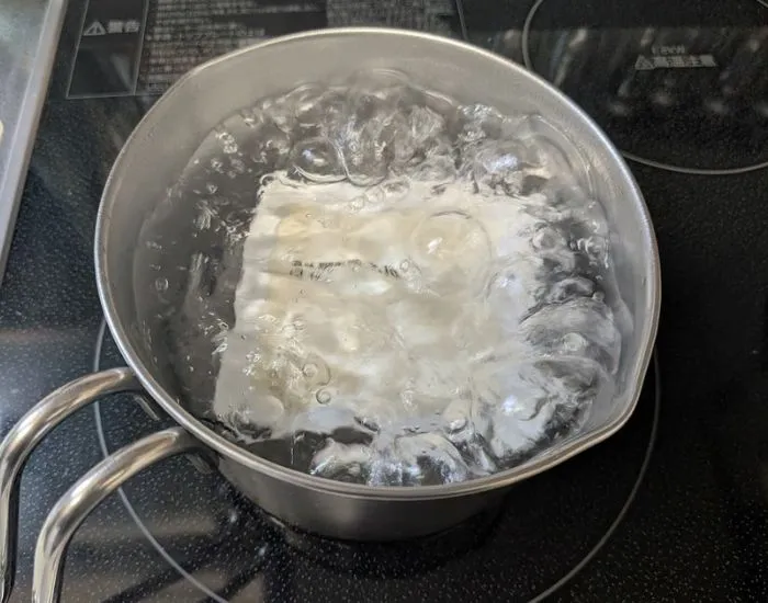 パックごと豆腐を鍋のお湯でゆでている写真（撮影：grape編集部）