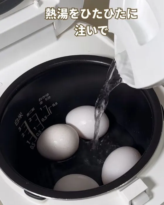 卵が入った炊飯器にお湯を足している様子